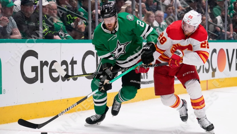 Dallas Stars defenseman Jani Hakanpaa (2) skates with the puck against Calgary Flames center Elias Lindholm (28) during the second period of Game 6 of an NHL hockey Stanley Cup first-round playoff series, Friday, May 13, 2022, in Dallas. (AP Photo/Tony Gutierrez)