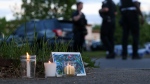 Police walk by a small memorial as they investigate after a shooting at a supermarket on May 14, 2022, in Buffalo, N.Y. (AP Photo/Joshua Bessex)