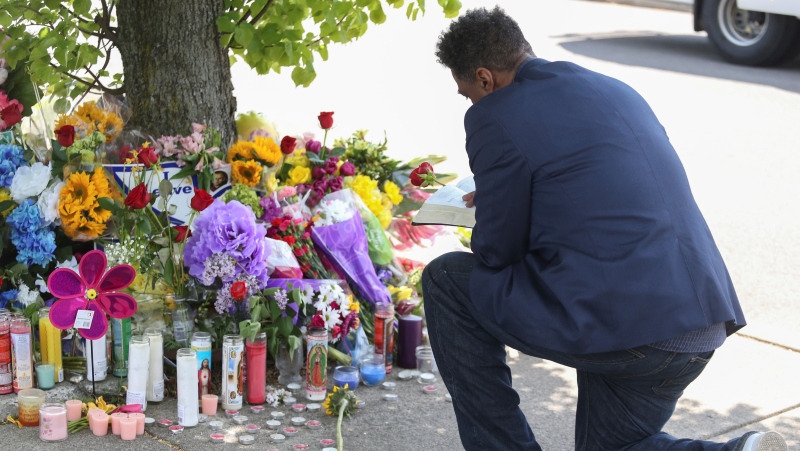 A man reads scripture at the site of a memorial honouring the victims of Saturday's shooting on May 15, 2022 in Buffalo, N.Y. A white 18-year-old wearing military gear and livestreaming with a helmet camera opened fire with a rifle at a supermarket, killing and wounding people in what authorities described as "racially motivated violent extremism." (AP Photo/Joshua Bessex)
