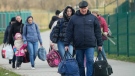 Refugees walk after fleeing the war from neighbouring Ukraine at the border crossing in Medyka, southeastern Poland, Monday, April 11, 2022. (AP Photo/Sergei Grits)