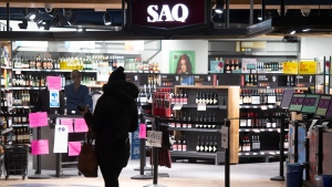 A woman walks by an SAQ outlet in Montreal, Tuesday, January 18, 2022. In an effort to curb the spread of COVID-19, vaccine passports will be mandatory to enter the SAQ and SQDC. THE CANADIAN PRESS/Graham Hughes
