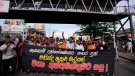 Members of Socialist Youth Union shout slogans and march towards Sri Lanka's police headquarters carrying a banner demanding the arrest of former prime minister Mahinda Rajapkasa for allegedly assaulting anti government protesters in Colombo, Sri Lanka, Monday, May 16, 2022. (AP Photo/Eranga Jayawardena)