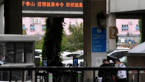 A security guard checks a man entering the Wanliu Campus of Peking University in Beijing, on May 17, 2022. (Ng Han Guan / AP) 