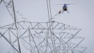 A lineman reaches for a lift from a helicopter on powerlines near Carstairs, Alta., on July 23, 2014. Alberta's utilities watchdog has shut down a plan from AltaLink to give ratepayers a refund. (THE CANADIAN PRESS/Jeff McIntosh)
