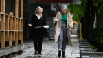 Courtney Shields, left, and Hannah Duhme wear the rain bonnets they purchased at a nearby pharmacy chain after they found out that umbrellas were completely sold out, as they walk with their takeout lunches in the rain in Ottawa, on Tuesday, May 17, 2022. (Justin Tang/THE CANADIAN PRESS) 