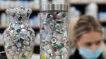 Jars full of empty COVID-19 vaccine vials are shown as a pharmacist works behind the counter at the Junction Chemist pharmacy during the COVID-19 pandemic in Toronto on Wednesday, April 6, 2022. (THE CANADIAN PRESS/Nathan Denette)