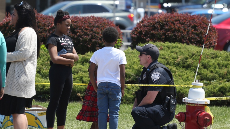 A Buffalo police officer talks to children at the scene of Saturday's shooting at a supermarket on Sunday, May 15, 2022, in Buffalo, N.Y. (AP Photo/Joshua Bessex)