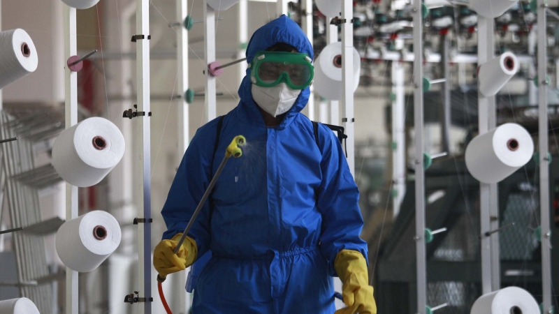 An employee of Songyo Knitwear Factory in Songyo district disinfects the work floor in Pyongyang, North Korea, May 18, 2022, after Kim Jong Un said Tuesday his party would treat the country's outbreak under the state emergency. (AP Photo/Jon Chol Jin)