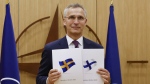 NATO Secretary-General Jens Stoltenberg displays documents as Sweden and Finland applied for membership in Brussels, Belgium, May 18, 2022. (Johanna Geron, Pool via AP)