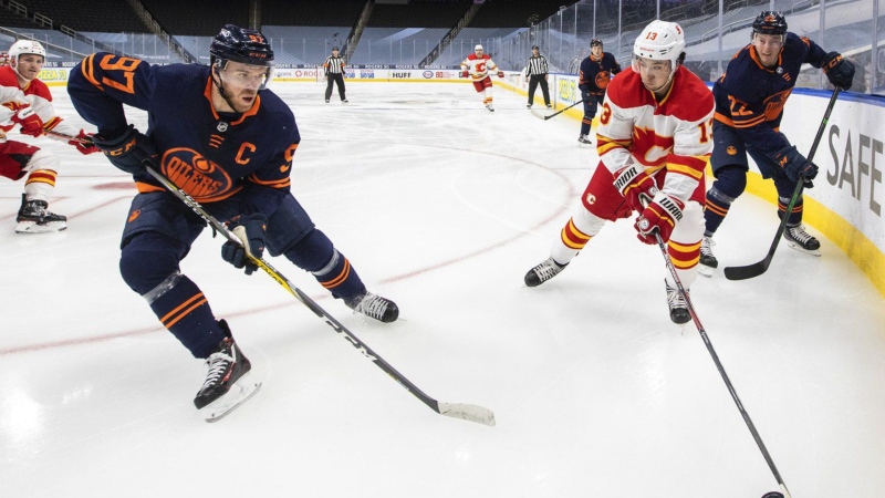 Edmonton Oilers' Connor McDavid (97) and Calgary Flames' Johnny Gaudreau (13) battle for the puck during first period NHL action in Edmonton on Saturday, May 1, 2021. (THE CANADIAN PRESS/Jason Franson)