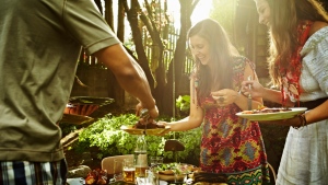 A group of friends enjoy a barbeque together in a backyard. (Getty Images) 