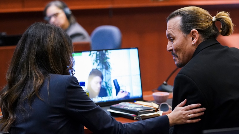 Actor Johnny Depp speaks with his attorney Camille Vasquez in the courtroom at the Fairfax County Circuit Courthouse in Fairfax, Va., Wednesday, May 18, 2022.  (Kevin Lamarque/Pool Photo via AP)