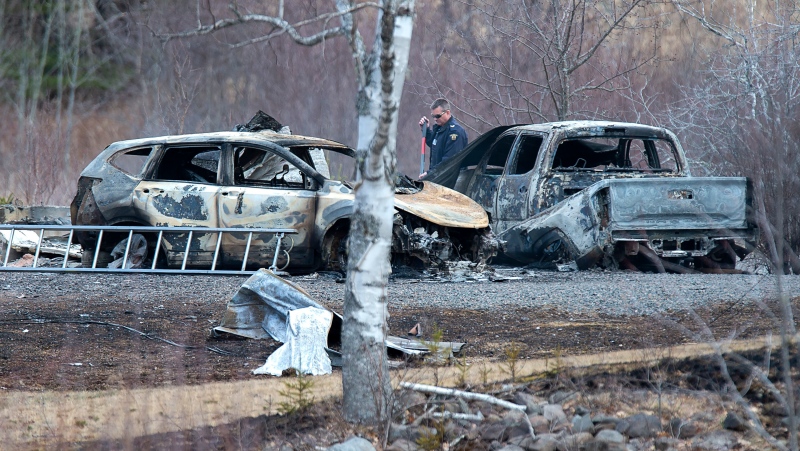 An RCMP investigator inspects vehicles destroyed by fire at the residence of Alanna Jenkins and Sean McLeod, both corrections officers, in Wentworth Centre, N.S. on Monday, April 20, 2020. (THE CANADIAN PRESS/Andrew Vaughan)