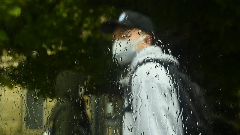 A person wearing a mask walks in the rain on a fall day during the COVID-19 pandemic in Toronto on Thursday, Oct. 15, 2020. THE CANADIAN PRESS/Nathan Denette