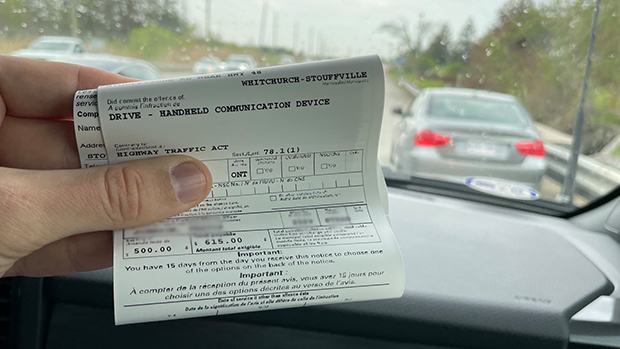 A York Regional Police officer holds a ticket for a driver accused of using his phone while travelling through Whitchurch-Stouffville, Ont., on Fri., May 20, 2022 (York Regional Police/Twitter)