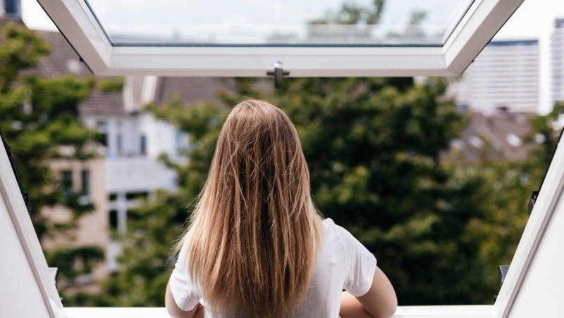 A photo fo a young girl looking out an open window. (Getty Images)