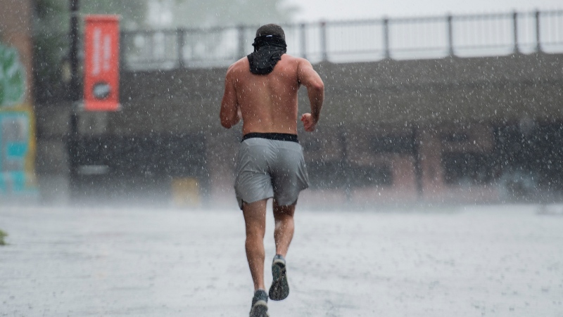 A man jogs through a torrential downpour of rain in Montreal, Monday, Sept. 6, 2021. A severe thunderstorm warning has been issued by environment Canada for the area. THE CANADIAN PRESS/Graham Hughes