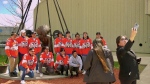 Members of the Nemaska Axemen pose for a photo with newly unveiled Fred Sasakamoose statue at SaskTel Centre. (Keenan Sorokan/CTV News Saskatoon)