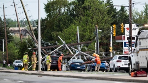 firefighters and utility workers work among downed power lines, poles and traffic lights that came down onto the roadway and onto motorists during a major storm, on Merivale Road in Ottawa, on Saturday, May 21, 2022. THE CANADIAN PRESS/Justin Tang 