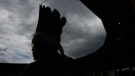 Skwelcampt, from Turtle Island, is silhouetted as he listens during a ceremony to mark the one-year anniversary of the announcement of the detection of the remains of children at an unmarked burial site at the former Kamloops Indian Residential School, in Kamloops, B.C., on Monday, May 23, 2022. THE CANADIAN PRESS/Darryl Dyck 