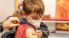 Pupil Marcel Schatt looks at the bandaid stuck to his puncture site after his vaccination in Cottbus, Germany on Jan.14, 2022. (Frank Hammerschmidt/dpa via AP)