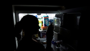 Stephanie Robb over looks the expiry date on a bottle of mustard in her fridge at her home in Toronto. THE CANADIAN PRESS/Nathan Denette
