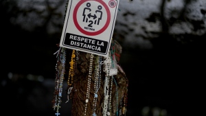 Rosary beads hang by a sign asking people to keep their distance amid the COVID-19 pandemic, in Salta, Argentina, on May 2, 2022. (Natacha Pisarenko / AP) 