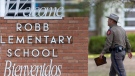 A state trooper walks past the Robb Elementary School sign in Uvalde, Texas, May 24, 2022, following a deadly shooting at the school. (William Luther/The San Antonio Express-News via AP)