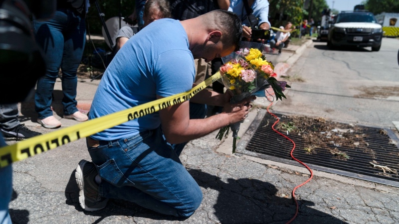 Joseph Avila, left, prays while holding flowers honouring the victims killed in Tuesday's shooting at Robb Elementary School in Uvalde, Texas, May 25, 2022. (AP Photo/Jae C. Hong)