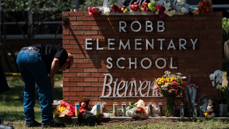 A law enforcement personnel lights a candle outside Robb Elementary School in Uvalde, Texas, Wednesday, May 25, 2022.(AP Photo/Jae C. Hong)