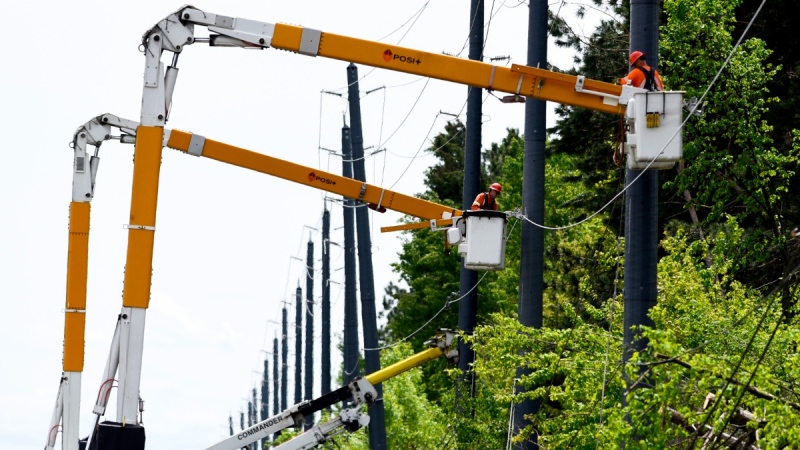 Utility workers use bucket lifts to repair lines along Hawthorne Road in Ottawa, on May 24, 2022. (Justin Tang / THE CANADIAN PRESS)