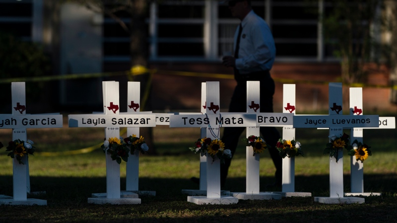 A law enforcement personnel walks past crosses bearing the names of Tuesday's shooting victims at Robb Elementary School in Uvalde, Texas, Thursday, May 26, 2022. (AP Photo/Jae C. Hong)