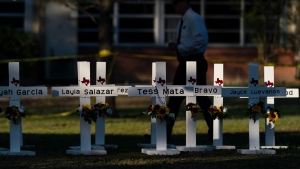 A law enforcement personnel walks past crosses bearing the names of Tuesday's shooting victims at Robb Elementary School in Uvalde, Texas, May 26, 2022. (AP Photo/Jae C. Hong)