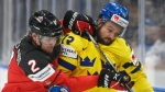 Emil Bemstrom of Sweden is challenged by Zach Wihtecloud of Canada, left, during the Hockey World Championship quarterfinal match, on May 26, 2022. (Vesa Moilanen / Lehtikuva via AP) 