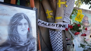 Yellow tape marks bullet holes on a tree and a portrait and flowers create a makeshift memorial at the site where Palestinian-American Al-Jazeera journalist Shireen Abu Akleh was shot and killed in the West Bank city of Jenin, May 19, 2022. (AP Photo/Majdi Mohammed, File)