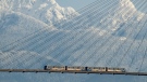 A SkyTrain crosses over the Fraser River past snow-capped mountains in the distance, in New Westminster, B.C., on Tuesday, Dec. 28, 2021. THE CANADIAN PRESS/Darryl Dyck