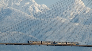 A SkyTrain crosses over the Fraser River past snow-capped mountains in the distance, in New Westminster, B.C., on Tuesday, Dec. 28, 2021. THE CANADIAN PRESS/Darryl Dyck 