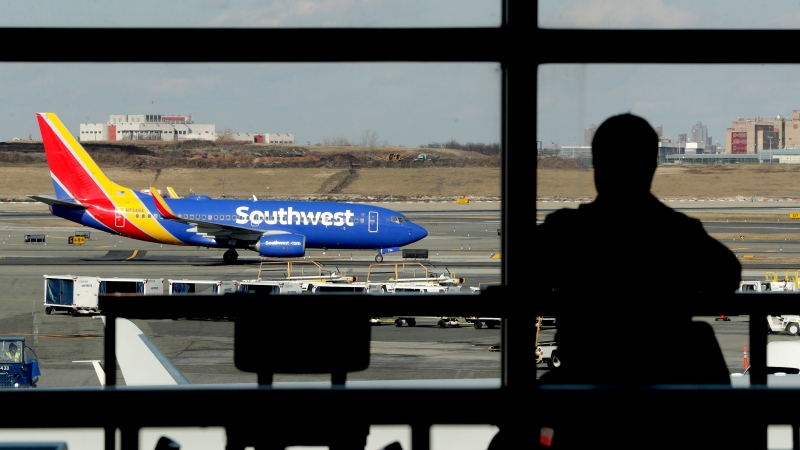 In this Jan. 25, 2019, file photo a Southwest Airlines jet moves on the runway as a person eats at a terminal restaurant at LaGuardia Airport in New York. (AP Photo/Julio Cortez, File)