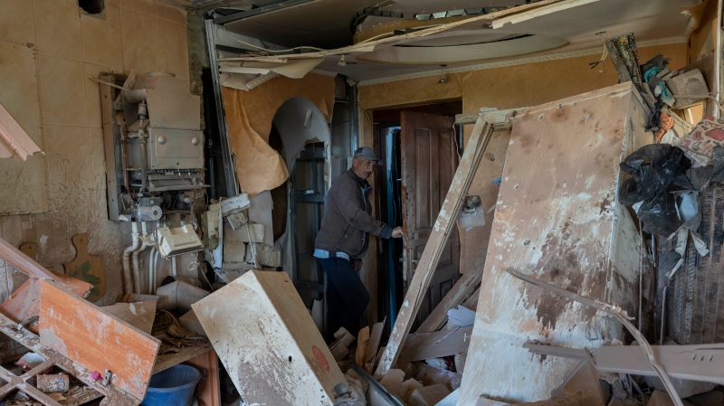 Resident Alexander, 67, checks the flat of his neighbor destroyed by shelling in Kutuzivka, near Kharkiv, eastern Ukraine, Friday, May 27, 2022. (AP Photo/Bernat Armangue) 
