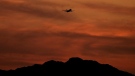 A passenger jet is silhouetted against the sky at dusk as it takes off from Sky Harbor Airport, Saturday, April 2, 2022, in Phoenix. (AP Photo/Charlie Riedel)