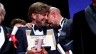 Writer/director Ruben Ostlund, winner of the Palme d'Or for 'Triangle of Sadness,' left, and writer/director Tarik Saleh, winner of the award for best screenplay for 'Boy from Heaven' celebrate during the awards ceremony of the 75th international film festival, Cannes, southern France, Saturday, May 28, 2022. (Photo by Joel C Ryan/Invision/AP)
