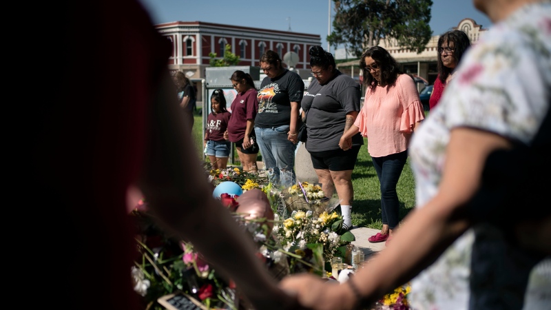 Hinojosa McKenzie, 28, fourth from left, prays for her cousin Eliahana Torres and other victims, at a memorial site for victims killed in the Robb Elementary school shooting, Saturday, May 28, 2022, in Uvalde, Texas. (AP Photo/Wong Maye-E) 