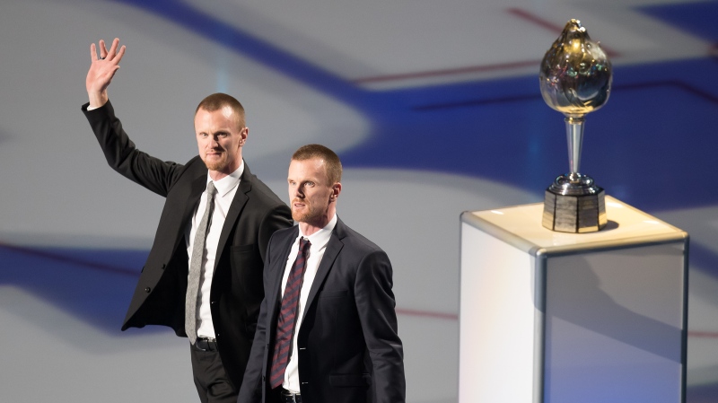 Former Vancouver Canucks players Henrik Sedin, left, and his twin brother Daniel Sedin, both of Sweden, walk onto the ice during a jersey retirement ceremony before an NHL hockey game in Vancouver, on Wednesday February 12, 2020. THE CANADIAN PRESS/Darryl Dyck 
