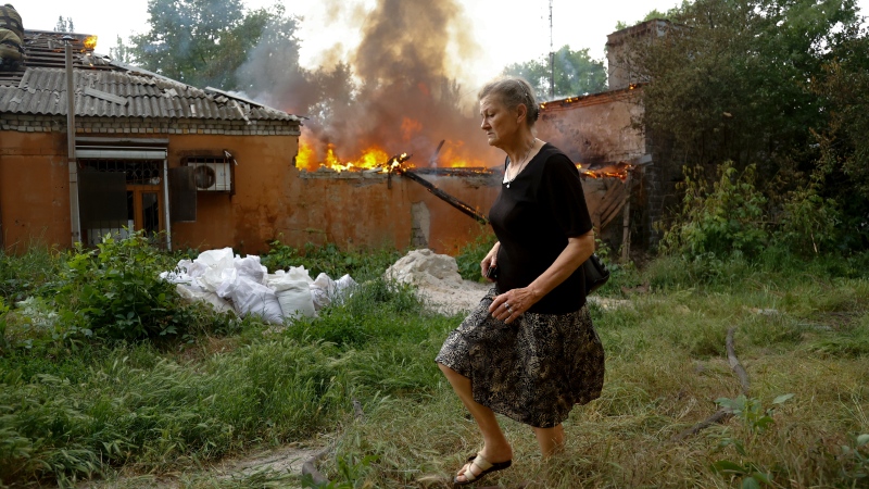 A woman runs from a house that's on fire after shelling in Donetsk, on the territory which is under the Government of the Donetsk People's Republic control, eastern Ukraine, Friday, June 3, 2022. (AP Photo/Alexei Alexandrov)