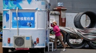 A woman gets a throat swab at a mobile coronavirus testing facility near a construction site in Beijing, Wednesday, June 8, 2022. People are required a negative COVID test result in the last 72 hours to enter some buildings and use public transportation. (AP Photo/Andy Wong)