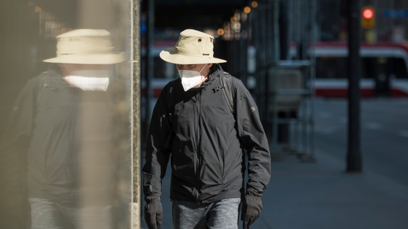 A pedestrian wears a mask as they walk through a quiet downtown in Toronto on Wednesday, April 7, 2021. THE CANADIAN PRESS/Tijana Martin