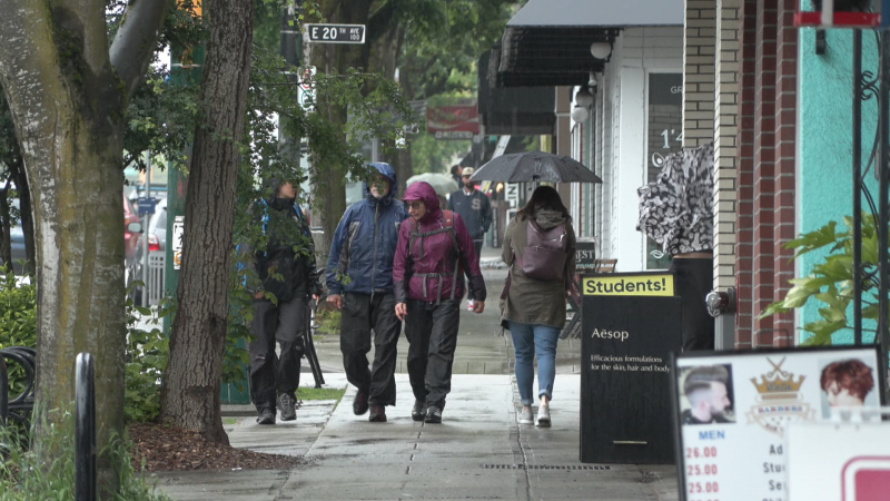 People walk through the rain on Main Street in Vancouver, B.C., on June 9, 2022. 