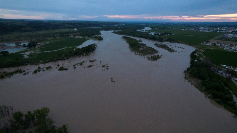The roaring Yellowstone River is seen from the air sweeping over trees and near homes Tuesday, June 14, 2022, in Billings, Mont. (AP Photo/Brittany Peterson)