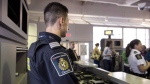 A Canadian Border Services agent stands watch at a gate on Tuesday, December 8, 2015. Dozens of people from Asia, Africa and Latin America who were planning to attend a major AIDS conference in Montreal say they've been denied visas, or have heard nothing from the Canadian government for weeks. THE CANADIAN PRESS/Darren Calabrese