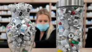 Containers full of empty COVID-19 vaccine vials are shown as a pharmacist works behind the counter at the Junction Chemist pharmacy during the COVID-19 pandemic in Toronto, April 6, 2022. THE CANADIAN PRESS/Nathan Denette
